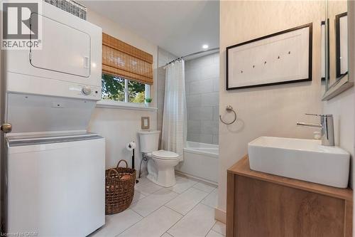 Full bath featuring stacked washer and clothes dryer, shower / bath combo with shower curtain, tile patterned flooring, and vanity - 181 Cedar Drive, Turkey Point, ON - Indoor