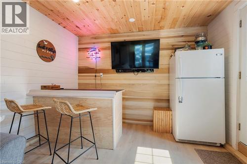 Bar area with freestanding refrigerator, wood walls, wooden ceiling, and light wood finished floors - 181 Cedar Drive, Turkey Point, ON - Indoor