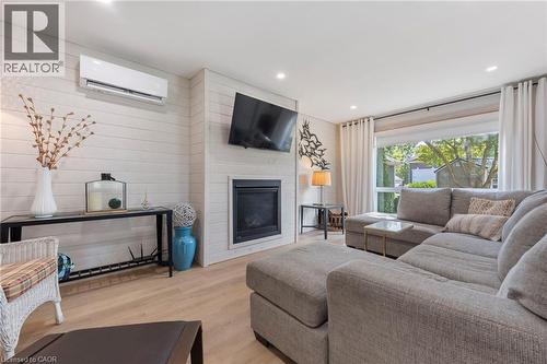 Living area featuring a wall mounted AC, wood finished floors, a fireplace, recessed lighting, and wood walls - 181 Cedar Drive, Turkey Point, ON - Indoor Photo Showing Living Room With Fireplace