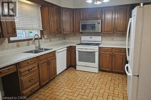 Kitchen with white appliances, light countertops, brick patterned floors, and tasteful backsplash - 226 Auburn Avenue, Hamilton, ON - Indoor Photo Showing Kitchen With Double Sink