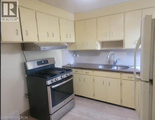 Kitchen featuring stainless steel gas range oven, freestanding refrigerator, cream cabinets, light wood finished floors - 51 East 16Th Street, Hamilton, ON - Indoor Photo Showing Kitchen With Double Sink