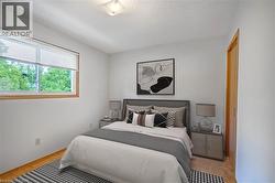 Bedroom with parquet flooring and a textured ceiling (virtually staged) - 
