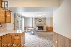 Kitchen with wainscoting, light countertops, wood walls, a fireplace, and wood finish cabinets - 