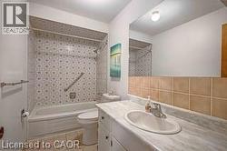 Bathroom with vanity, shower / tub combination, light tile patterned floors, and tile walls - 