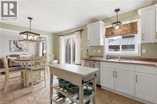 Kitchen featuring white cabinets, light tile patterned flooring, a chandelier, and dishwasher - 84 Duncairn Crescent, Hamilton, ON - Indoor