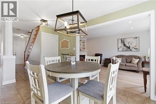 Dining area featuring decorative columns, suspended lighting, light tile patterned flooring, and a fireplace - 84 Duncairn Crescent, Hamilton, ON - Indoor Photo Showing Dining Room