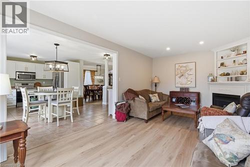 Living area featuring a fireplace, light wood finished floors, and suspended lighting - 84 Duncairn Crescent, Hamilton, ON - Indoor Photo Showing Living Room With Fireplace