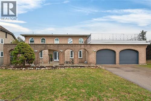 View of front of house featuring driveway, an attached garage, brick siding, and a front yard - 22 Woodside Drive, Hamilton, ON - Outdoor