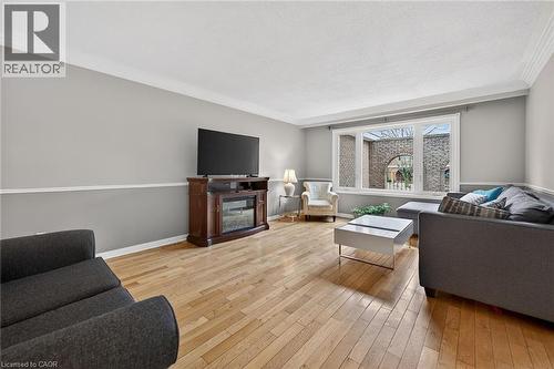 Living area featuring light wood-type flooring, crown molding, and a glass covered fireplace - 22 Woodside Drive, Hamilton, ON - Indoor Photo Showing Living Room