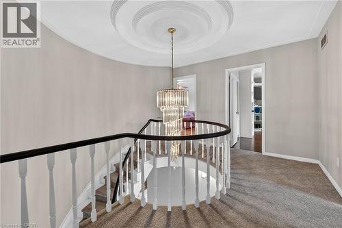 Stairway featuring suspended lighting, carpet flooring, and a tray ceiling - 22 Woodside Drive, Hamilton, ON - Indoor Photo Showing Other Room