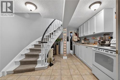 Kitchen with electric stove, white cabinets, light countertops, a textured ceiling, and light tile patterned floors - 22 Woodside Drive, Hamilton, ON - Indoor