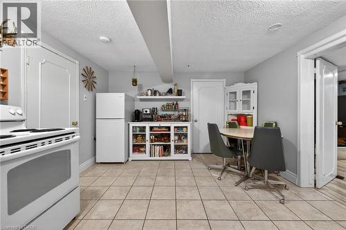 Kitchen with white appliances, a textured ceiling, white cabinets, open shelves, and light tile patterned floors - 22 Woodside Drive, Hamilton, ON - Indoor Photo Showing Kitchen