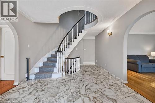 Stairs featuring arched walkways, crown molding, and marble look tiles - 22 Woodside Drive, Hamilton, ON - Indoor Photo Showing Other Room