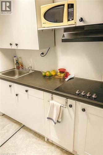 Kitchen with white cabinetry, ventilation hood, black electric cooktop, dark countertops, and light tile patterned floors - 988 Prosperity Court, London, ON - Indoor Photo Showing Kitchen With Double Sink