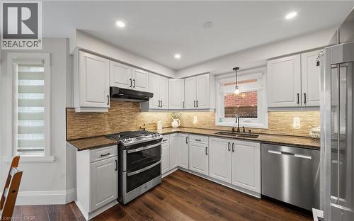 Kitchen with white cabinets, dark stone countertops, stainless steel appliances, and dark wood-style flooring - 4516 Gullfoot Circle, Mississauga, ON - Indoor Photo Showing Kitchen With Upgraded Kitchen