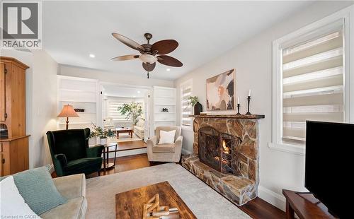 Living room featuring a stone fireplace, dark wood finished floors, built in features, and a ceiling fan - 4516 Gullfoot Circle, Mississauga, ON - Indoor Photo Showing Living Room With Fireplace