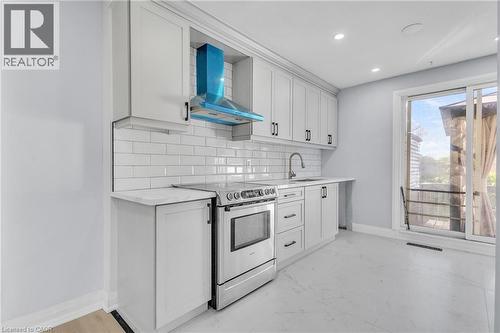 Kitchen featuring stainless steel range with electric stovetop, white cabinetry, tasteful backsplash, light stone counters, and recessed lighting - 84 Avalon Place, Kitchener, ON - Indoor Photo Showing Kitchen