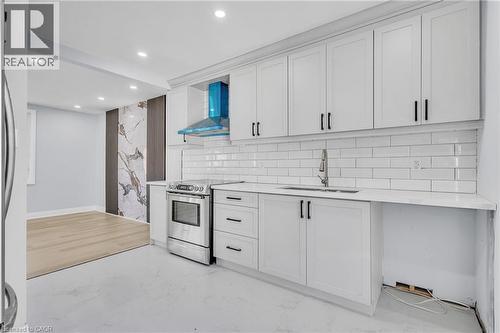 Kitchen featuring electric range, light stone counters, light marble finish flooring, decorative backsplash, and white cabinets - 84 Avalon Place, Kitchener, ON - Indoor Photo Showing Kitchen