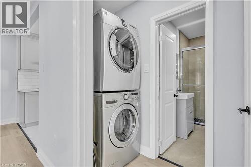 Laundry area with stacked washer / dryer and light wood-style flooring - 84 Avalon Place, Kitchener, ON - Indoor Photo Showing Laundry Room