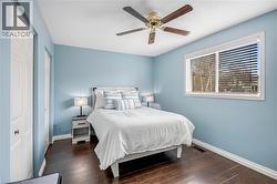 Bedroom with multiple closets, dark wood-style flooring, and ceiling fan - 