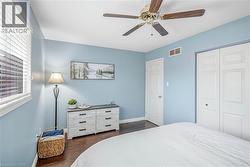 Bedroom featuring dark wood-style floors, ceiling fan, and a closet - 