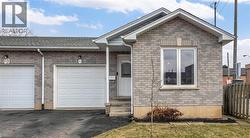 Ranch-style house featuring brick siding, asphalt driveway, a garage, and roof with shingles - 