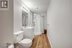 Full bathroom featuring vanity, a shower stall, a drop ceiling, and light wood-style flooring - 