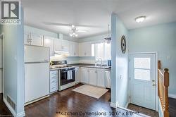 Kitchen featuring white appliances, white cabinetry, dark wood-style flooring, and a ceiling fan - 