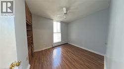 Unfurnished bedroom with dark wood-style flooring, a baseboard radiator, and ceiling fan - 