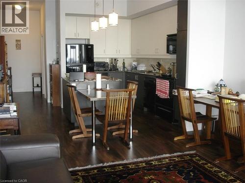 Dual tone kitchen featuring dark countertops, dark wood-style floors, black appliances, a kitchen bar, and a kitchen island - 191 King Street S Unit# 712, Waterloo, ON - Indoor