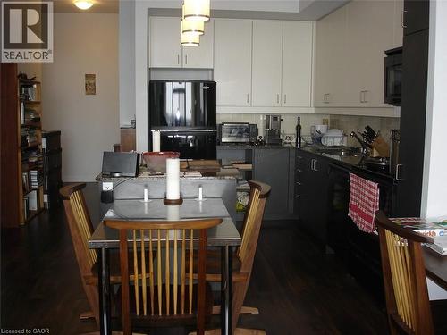 Kitchen featuring tasteful backsplash, dark wood-type flooring, black appliances, and dual tone cabinets - 191 King Street S Unit# 712, Waterloo, ON - Indoor