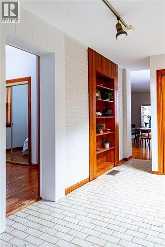 Hallway featuring rail lighting, brick wall, built in shelves, and brick patterned floors - 218 Bay Street S, Hamilton, ON 