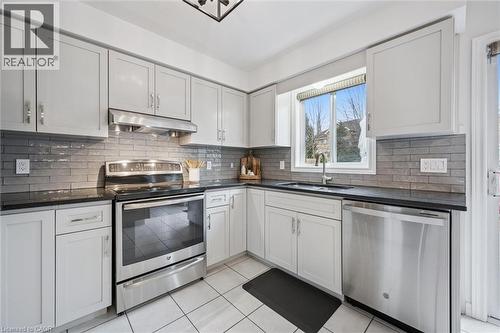 Kitchen with stainless steel appliances, light tile patterned floors, white cabinetry, and dark stone countertops - 68 Newman Drive, Cambridge, ON - Indoor Photo Showing Kitchen