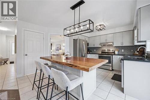 Kitchen with butcher block countertops, stainless steel appliances, light tile patterned floors, a breakfast bar area, and a kitchen island - 68 Newman Drive, Cambridge, ON - Indoor