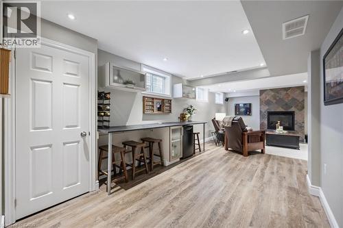 Indoor dry bar with recessed lighting, light wood finished floors, a fireplace, and dark countertops - 68 Newman Drive, Cambridge, ON - Indoor Photo Showing Other Room With Fireplace