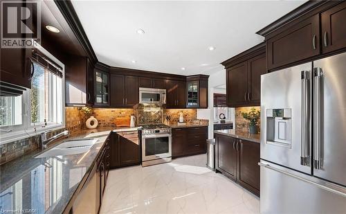 Kitchen featuring stainless steel appliances, dark wood finish cabinetry, dark stone countertops, and recessed lighting - 1550 Woodeden Drive, Mississauga, ON - Indoor Photo Showing Kitchen With Double Sink With Upgraded Kitchen