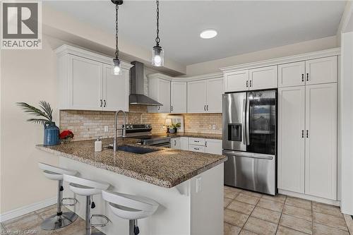 Kitchen featuring a kitchen breakfast bar, a peninsula, stainless steel appliances, white cabinets, and light tile patterned floors - 100 Garinger Crescent, Binbrook, ON - Indoor Photo Showing Kitchen With Stainless Steel Kitchen