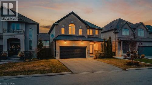View of front facade with brick siding, driveway, an attached garage, and a yard - 100 Garinger Crescent, Binbrook, ON - Outdoor With Facade