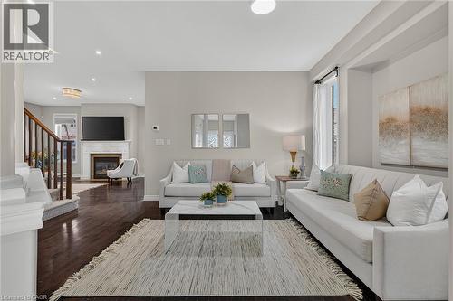 Living room featuring healthy amount of natural light, a glass covered fireplace, dark wood-style floors, and recessed lighting - 100 Garinger Crescent, Binbrook, ON - Indoor Photo Showing Living Room With Fireplace