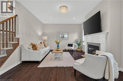 Living area with dark wood-style flooring and a fireplace with flush hearth - 100 Garinger Crescent, Binbrook, ON - Indoor Photo Showing Living Room With Fireplace