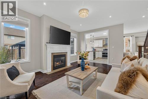 Living area with dark wood-style floors, a fireplace with flush hearth, recessed lighting, and a barn door - 100 Garinger Crescent, Binbrook, ON - Indoor Photo Showing Living Room With Fireplace