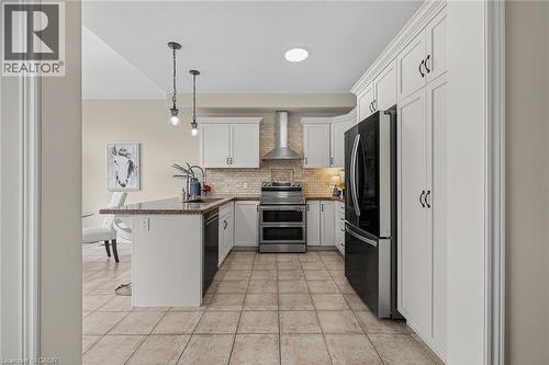 Kitchen featuring a peninsula, a kitchen bar, freestanding refrigerator, double oven range, and pendant lighting - 100 Garinger Crescent, Binbrook, ON - Indoor Photo Showing Kitchen With Stainless Steel Kitchen With Upgraded Kitchen