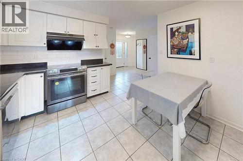 Kitchen featuring white cabinets, stainless steel appliances, decorative backsplash, and extractor fan - 62 Como Place, Hamilton, ON - Indoor Photo Showing Kitchen
