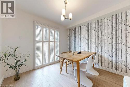 Dining space featuring an accent wall, wallpapered walls, light wood-style flooring, and a chandelier - 62 Como Place, Hamilton, ON - Indoor Photo Showing Dining Room