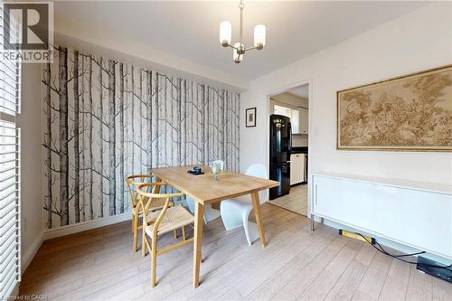 Dining area with light wood-style floors, a chandelier, and an accent wall - 62 Como Place, Hamilton, ON - Indoor Photo Showing Dining Room