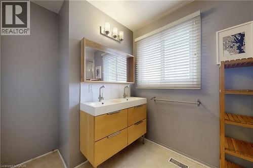 Bathroom featuring double vanity, backsplash, and light tile patterned floors - 62 Como Place, Hamilton, ON - Indoor Photo Showing Bathroom