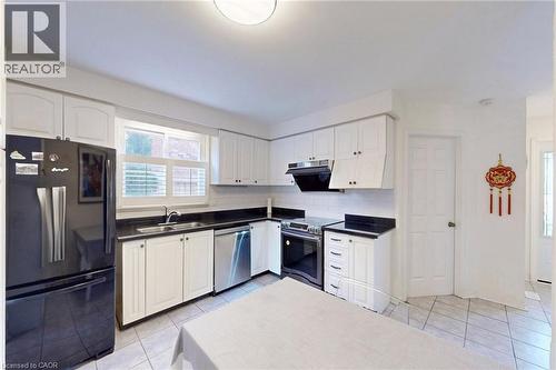 Kitchen with stainless steel appliances, white cabinetry, and dark countertops - 62 Como Place, Hamilton, ON - Indoor Photo Showing Kitchen With Double Sink