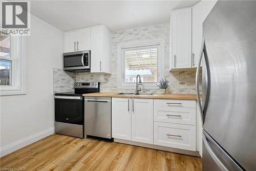 Kitchen with stainless steel appliances, butcher block counters, white cabinetry, and backsplash - 699 Frederick Street, Kitchener, ON - Indoor Photo Showing Kitchen With Stainless Steel Kitchen With Double Sink