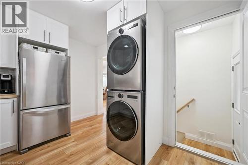 Laundry area with stacked washing machine and dryer and light wood-style floors - 699 Frederick Street, Kitchener, ON - Indoor Photo Showing Laundry Room