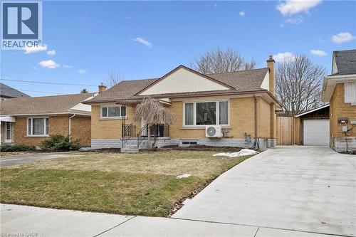 View of front of house featuring a chimney, brick siding, a front lawn, an outdoor structure, and a garage - 699 Frederick Street, Kitchener, ON - Outdoor With Facade